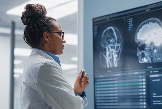 A doctor reviews brain scans on a monitor in a hospital.